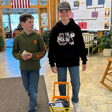 two students behind a mini shopping cart