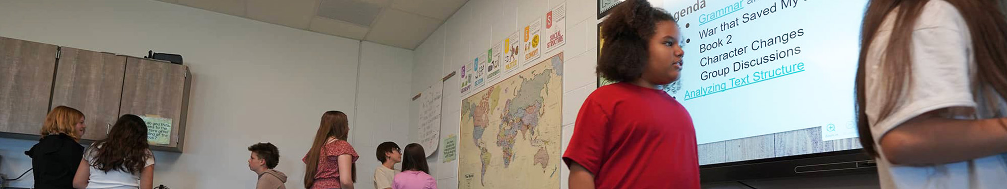 Middle school girl in red t-shirt looking at the projection board in the classroom