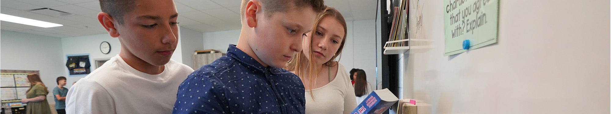 Three middle school students looking at a book together