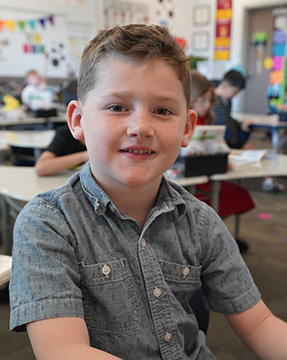 Happy elementary student looking up from his desk