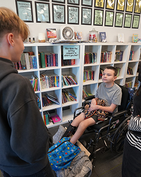 Two students talking next to book shelves
