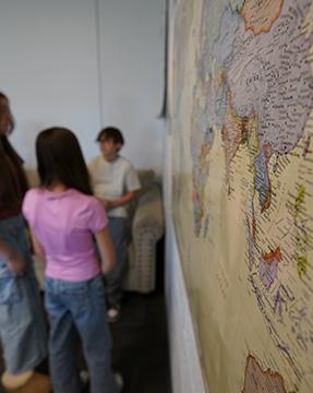 Students talking in a classroom next to a big map on the wall