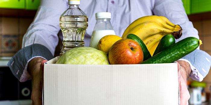 Community member holding a big box filled with fresh fruits and vegetables