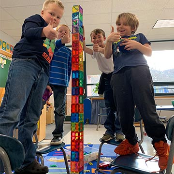 Four boys stacking a huge tower of magnet tiles