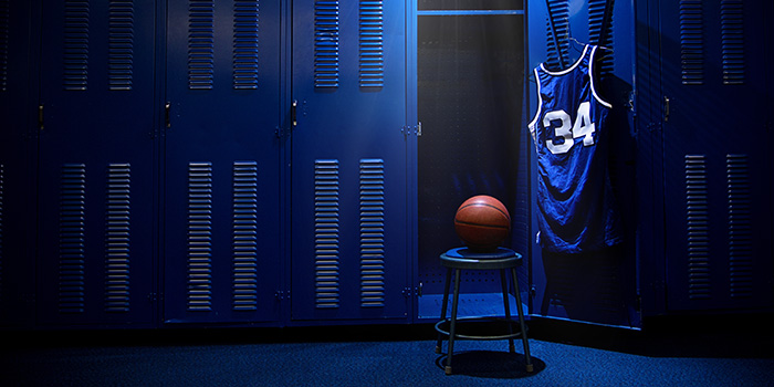 Basketball on a stool in a locker room with a jersey hanging on a locker door