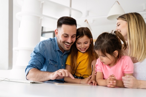 two parents looking at tablet with two kids