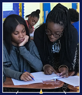 Two students reading papers at desk