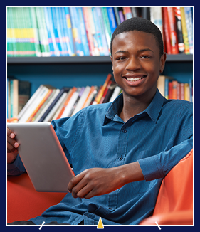 boy sitting in library reading on a tablet