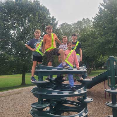 students wearing safety sashes standing on playground equipment