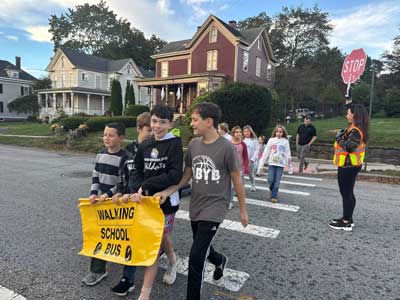 students crossing a street holding a banner that reads Walking School Bus