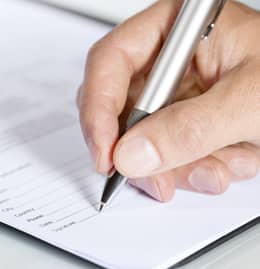 Hand holding a pen filling out a registration form