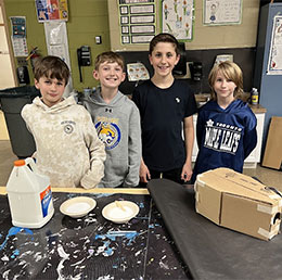 Four students working on a project with glue