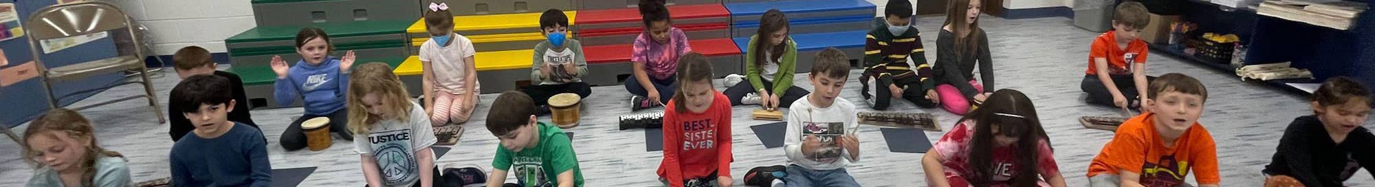 students sitting on the floor playing musical instruments