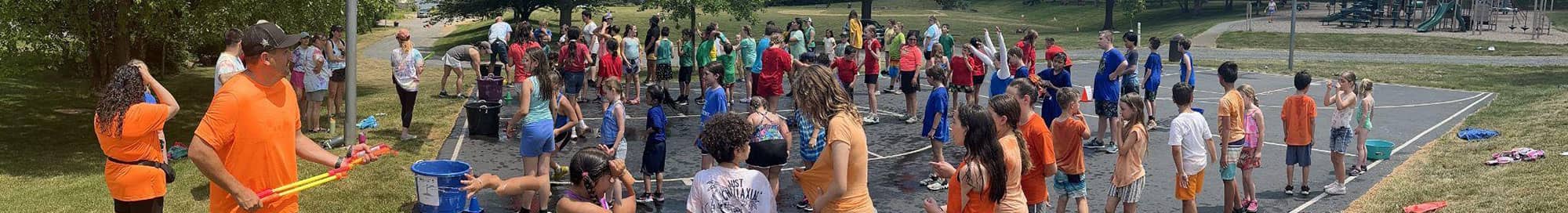 large group of students in colorful shirts playing water games outside