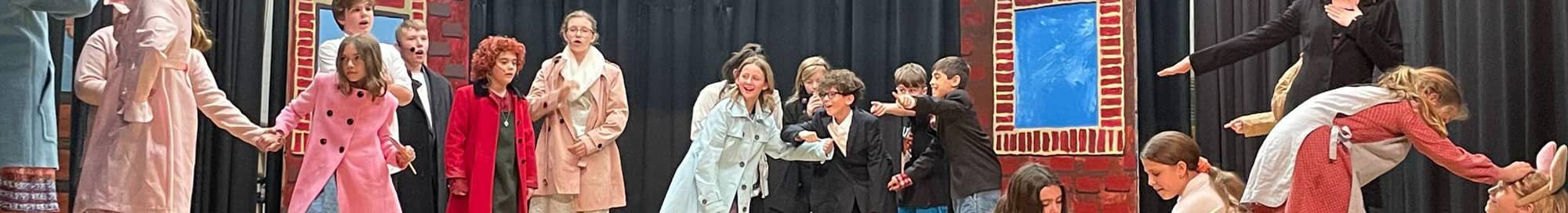 subpagebanner_schoolinfo students acting on stage in a play