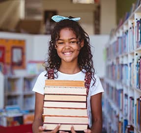 Smiling girl holding a stack of books
