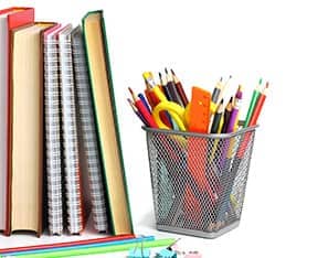 Books and notebooks next to a pencils, clips, and a wire container with school supplies in it