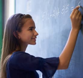student writing on chalkboard