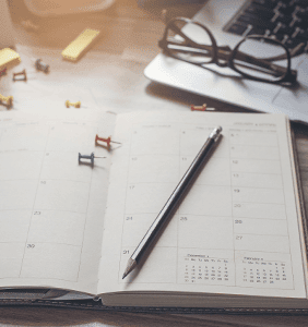 Open calendar planner with a pen on top and glasses above