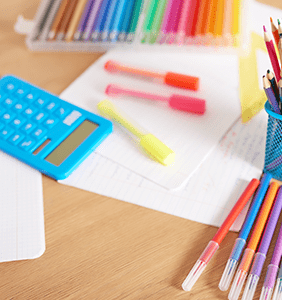 Colored markers, blank paper, and a calculator on a desk