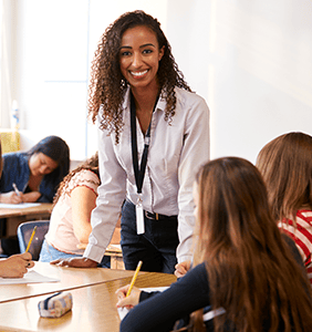 Teacher standing by table talking to two students