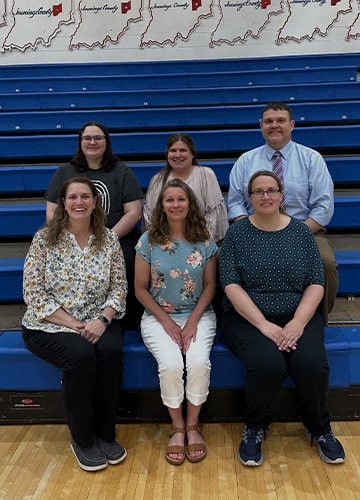Six staff members sitting on the bleachers