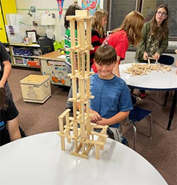 Student with a tall wood tower