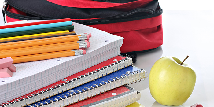 Assorted school supplies, backpack, and apple