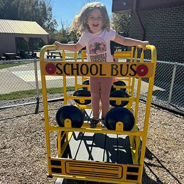 A student on outdoor equipment that looks like a school bus