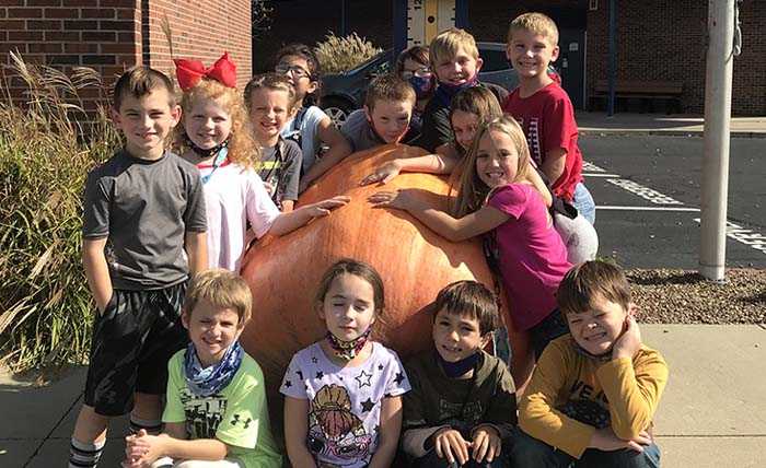 Group of students smiling next to a giant squash