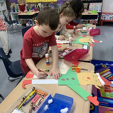 Students working on giant Christmas elf decorations in class
