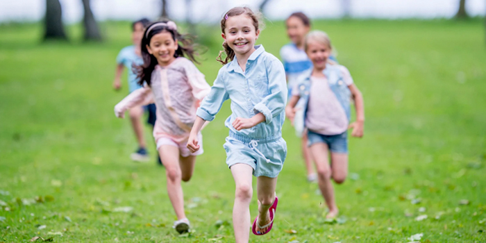 Happy students running outside on a green field