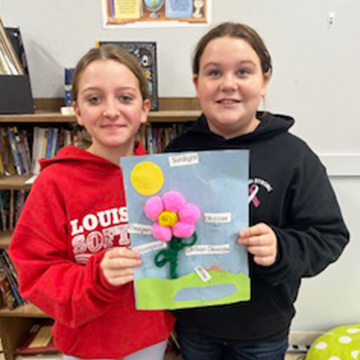 Two students holding up a flower project