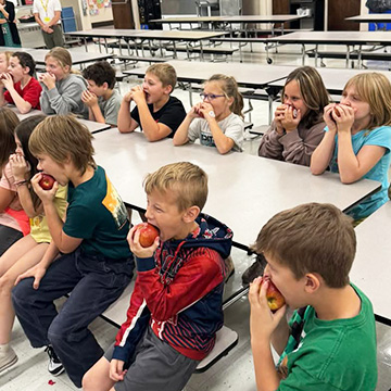Third grade students eating apples