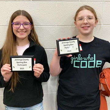 Two happy students holding up spelling bee awards