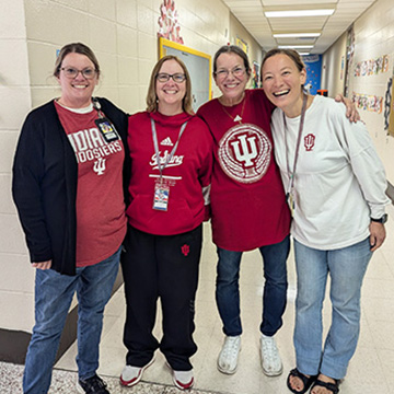 Four happy staff members in the school hallway