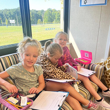 Happy students reading on a couch with view of the school playground