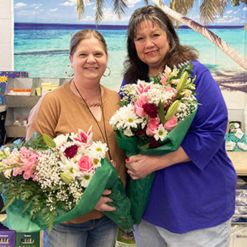 Two staff members holding flowers