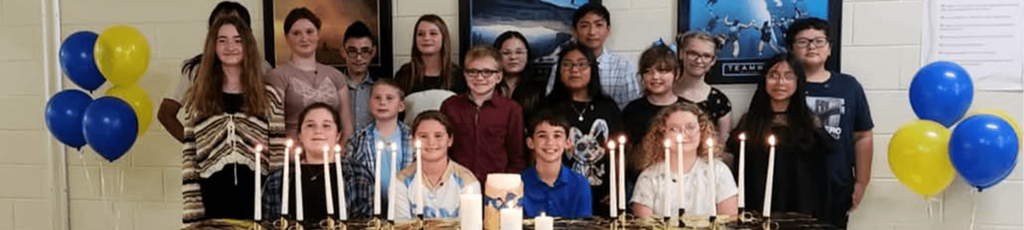 Students gathered behind a table with candles