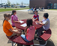 Many students sitting around a table making observations