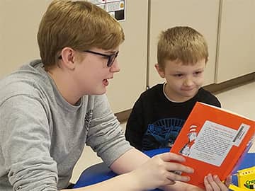 older person reading to a younger student
