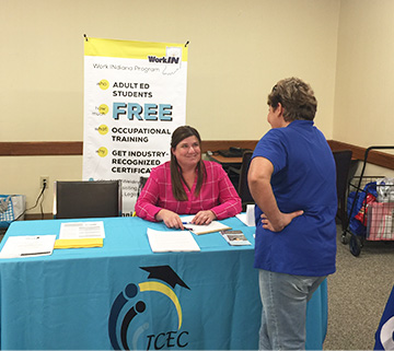 School representative talking to a women from behind an information table