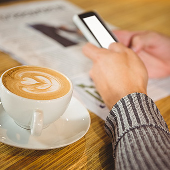 Parent looking for information on her phone next to coffee