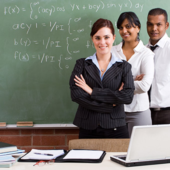 Three teachers behind a classroom desk