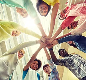 group of students in circle with hands together in middle