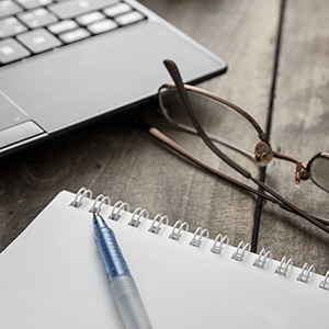 laptop, glasses, and notepad sitting on a desk
