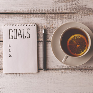 notepad with Goals written at the top with a cup of tea to the side