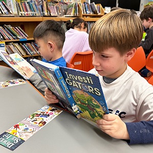 Two boys reading books in the library