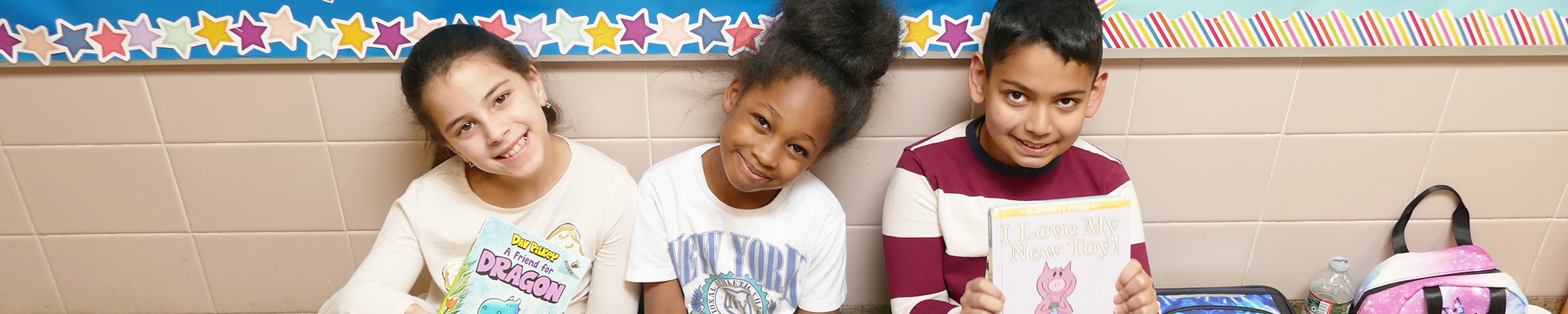 Three happy students sitting in the school hallway