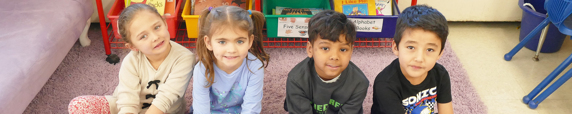 Four happy students sitting in the classroom